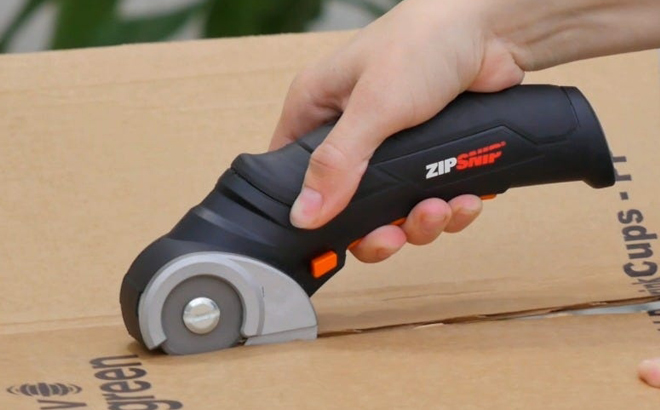 A Hand cutting a Peper Box with Worx 4V ZipSnip Electric Rechargeable Cordless Electric Scissors