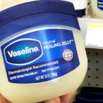 A Hand holding a 13 Ounce Jar of Vaseline Healing Jelly