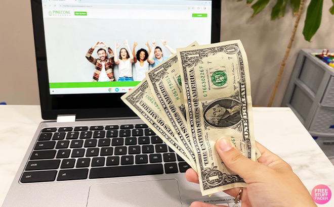 A Person Holding Money in front of Laptop