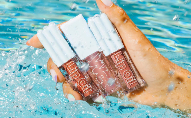 A Person Holding Three Kosas Wet Lip Oil Gloss