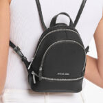 A Person Wearing Michael Kors Outlet Rhea Extra Small Pebbled Leather Backpack