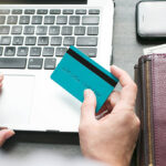 A Person Working on a Laptop while Holding a Card