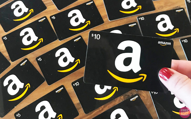 A Person Holding an Amazon Gift Card in front of a Table with More Amazon Gift Cards