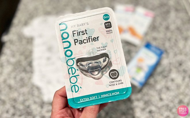 Hand Holding Nano Bebe Pacifier in Front of a Table Top