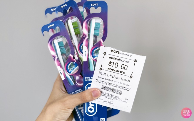 A Hand Holding Toothbrushes and CVS ExtraBucks
