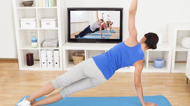 A Woman Working Out at Home to a Video
