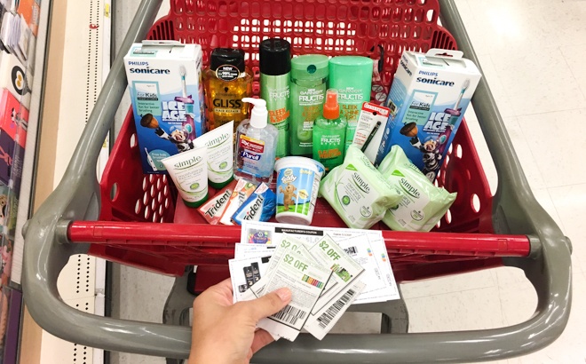 A Hand Holding Coupons in Front of a Target Cart Full of Products