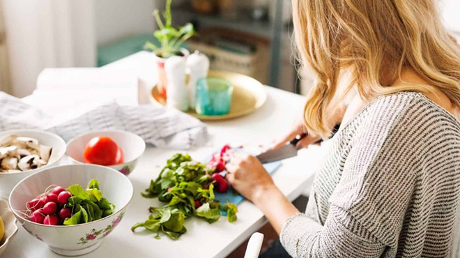 A Woman Cutting Fresh Vegetables on a Kitchen Counter