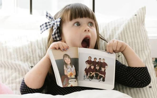 Surprised little girl reacts to childhood photos with an adorable expression