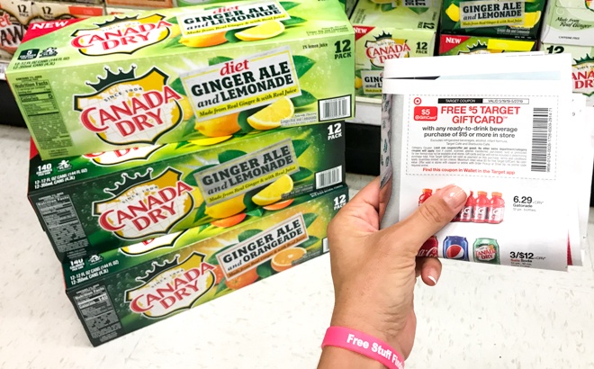 A Hand Holding Coupons Next to Canada Dry Ginger Ale 12-Packs